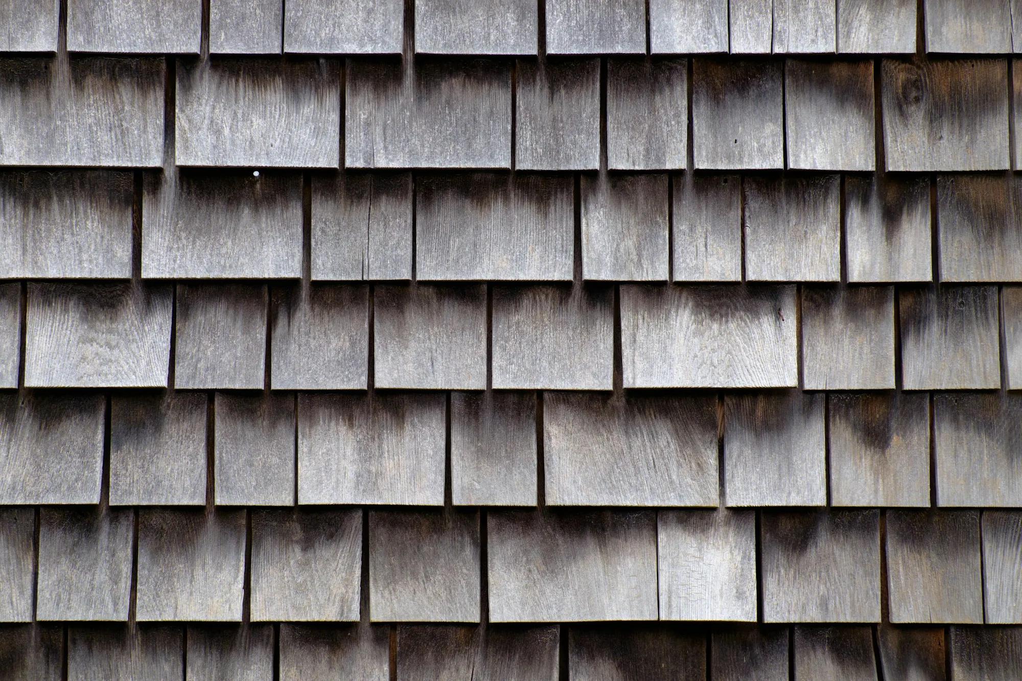 Close-up of split wood shakes on a roof, the surface that cedar shake roof care in Duluth's humid climate aims to keep dry