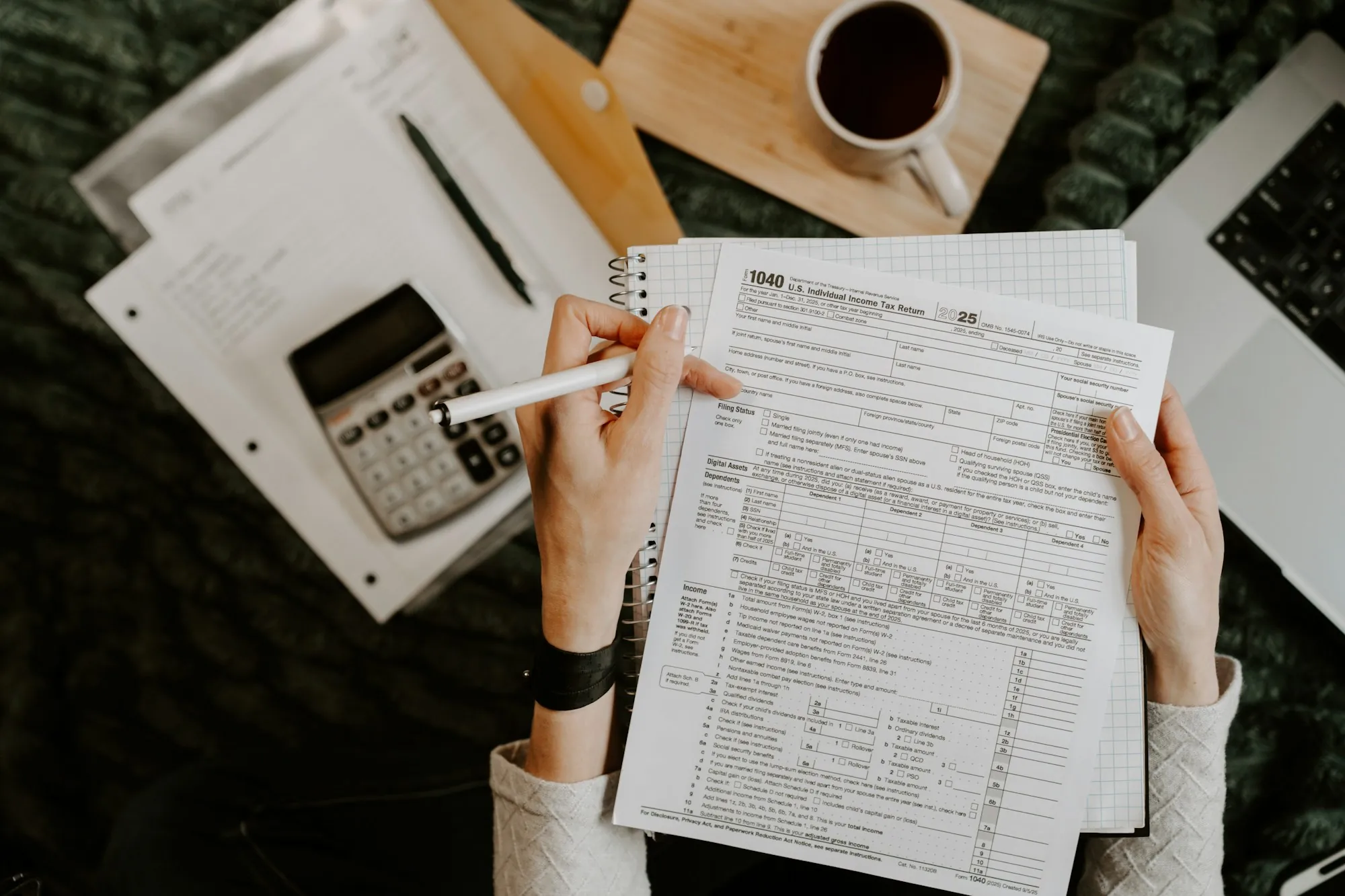 Hands filling out a form beside a calculator and coffee