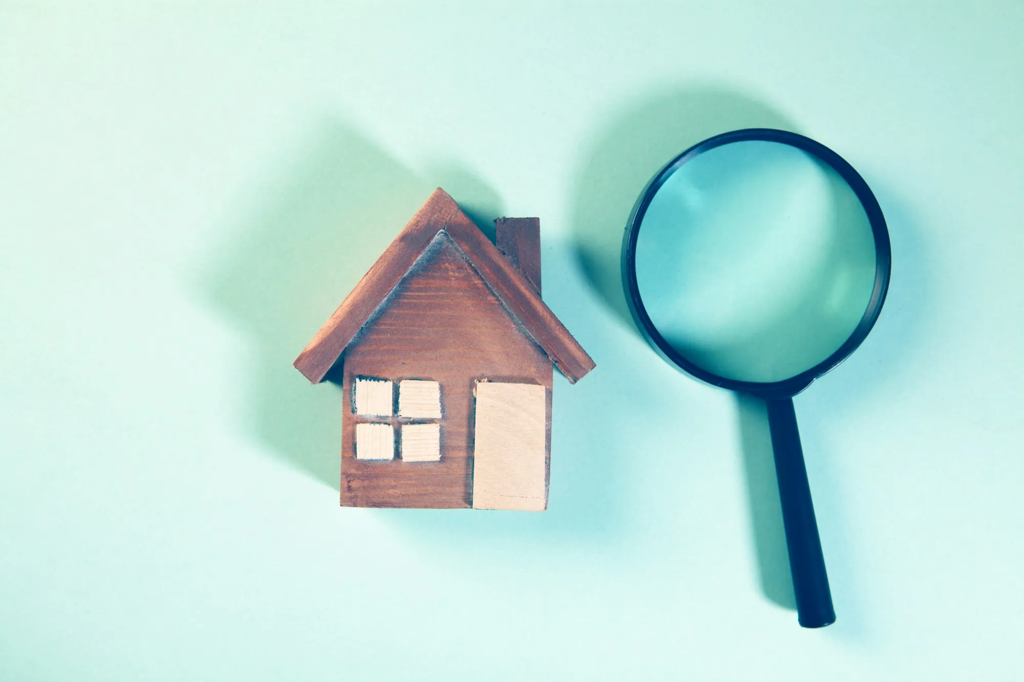 Small wooden house model next to a magnifying glass