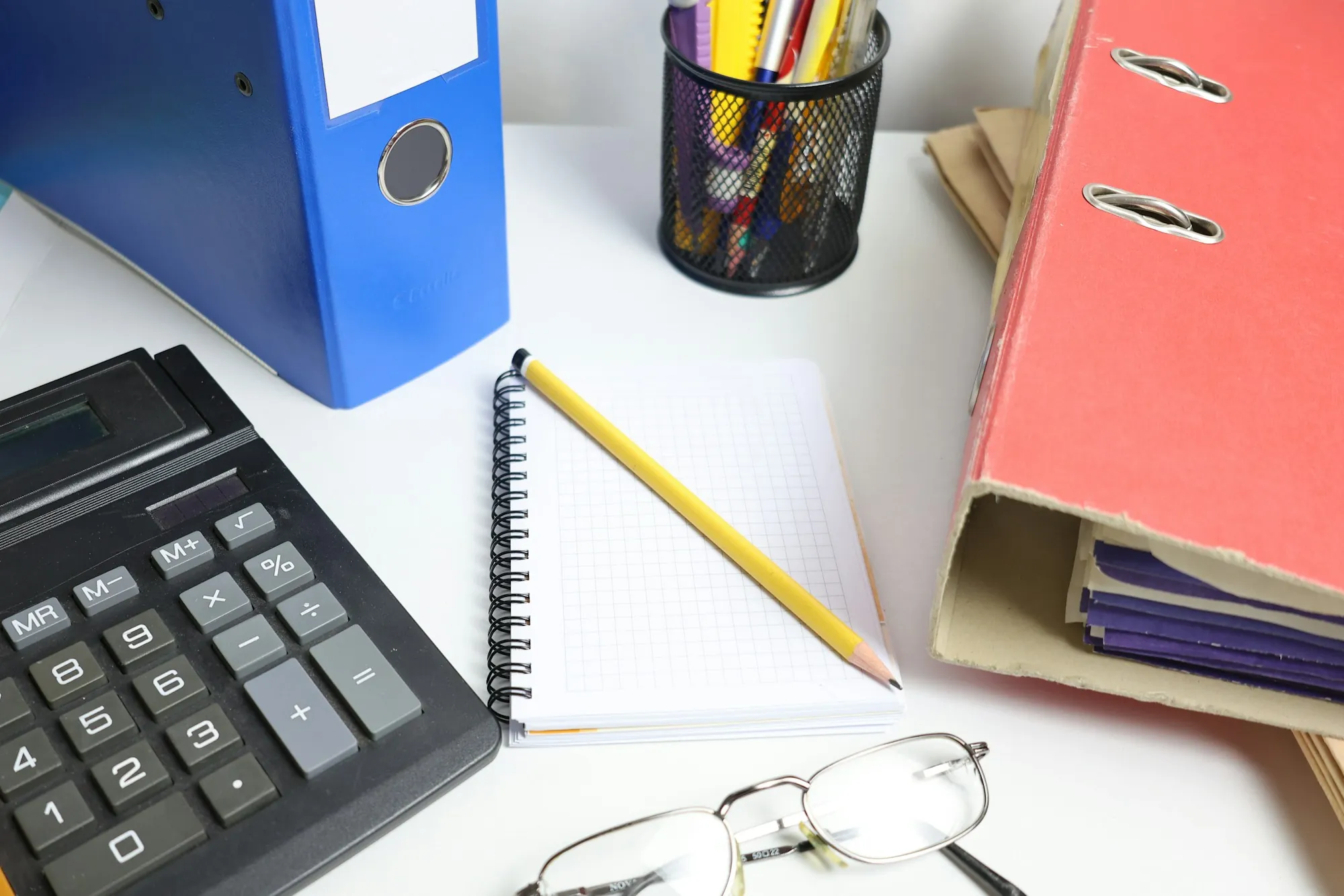Desk with a calculator, notebook, pencil and binders