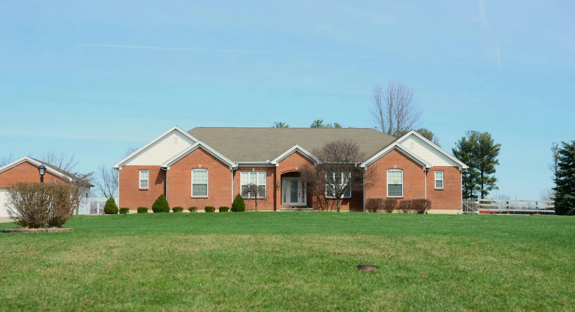 Red brick ranch home with a broad lawn in spring